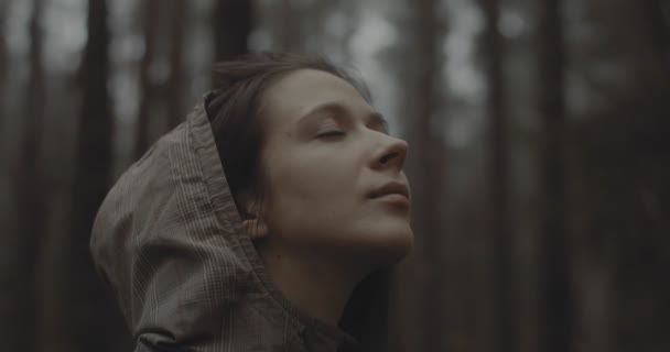 Portret młodej dziewczyny stojącej w lesie i marzącej o czymś. Piękna kobieta bez makijażu spogląda w niebo i cieszy się przyrodą. nastolatka dziewczyna twarz otwarcie i odzież oczy na zewnątrz — Wideo stockowe