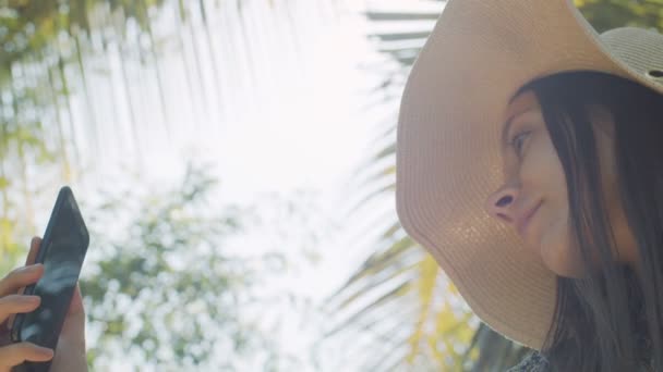 Chica feliz haciendo foto en el teléfono inteligente en la naturaleza vista de fondo de ángulo bajo. Mujer viajera fotografiando en el teléfono móvil sonriendo con satisfacción de cerca. Turismo viaje verano vacaciones concepto — Vídeo de stock