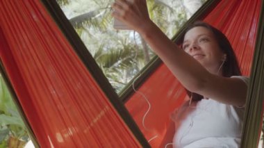 Çekici bir kadın arkadaşlarıyla açık hava yeşil arka planda görüntülü sohbet kullanarak konuşur. Akıllı telefon konuşması yapan kadın gezgin yavaş çekimde yakınlaşıyor. İnternet üzerinden karantina ilişkileri