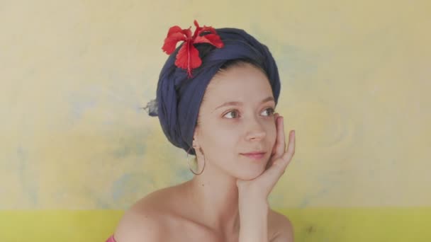 Retrato de mujer caucásica con turbante azul con flores sobre fondo amarillo claro. Sonriente chica natural posando al aire libre estilo tropical copiar el espacio de texto en cámara lenta. Cuidado de la piel de moda femenina — Vídeos de Stock