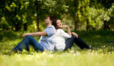Genç çift arka kalkmakistediğini için oturma parkta çimlere Smilin