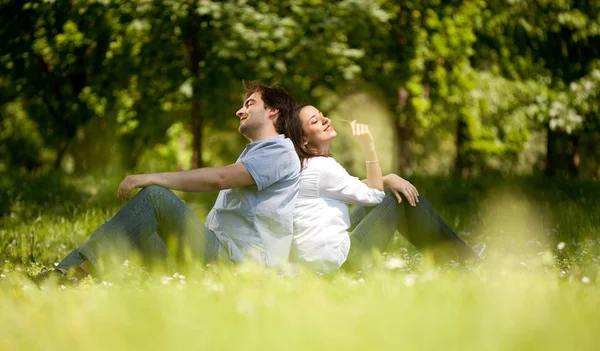 Genç çift arka kalkmakistediğini için oturma parkta çimlere Smilin — Stok fotoğraf