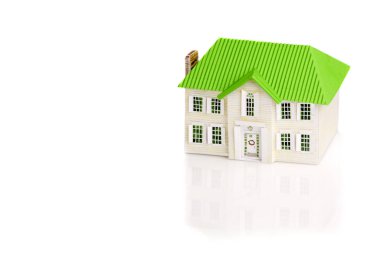 Beyaz zemin üzerine yeşil çatılı bir oyuncak ev