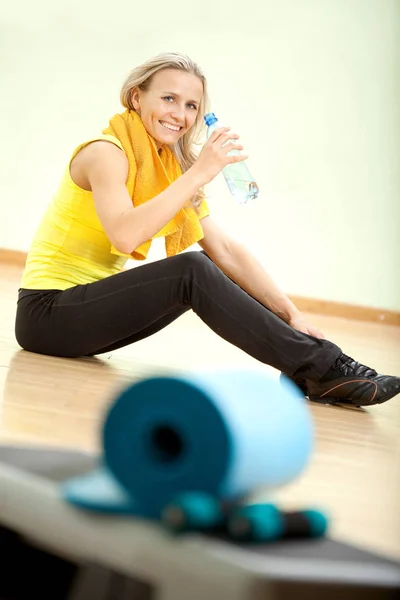 Beautiful young woman after fitness drinks water from a plastic — Stock Photo, Image