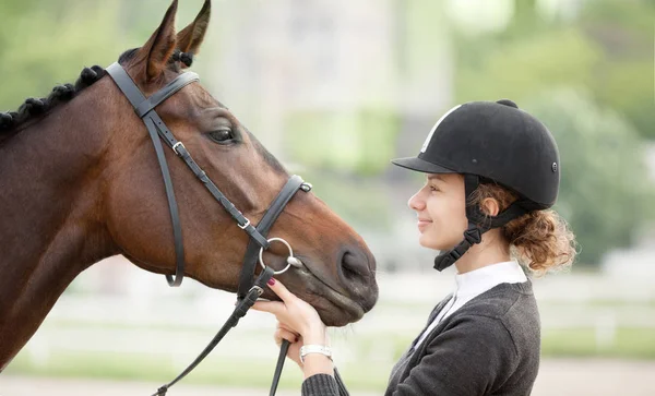 Attraktive junge Frau schaut auf ihr Pferd — Stockfoto