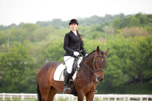 Attraktive junge Frau im Jockey-Anzug reitet Pferd — Stockfoto