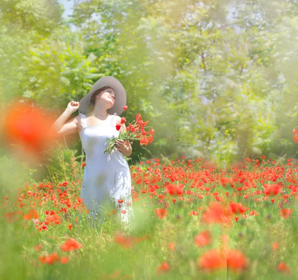 Charmante jonge vrouw verzamelt rode bloemen in een weide. Ze is dr — Stockfoto