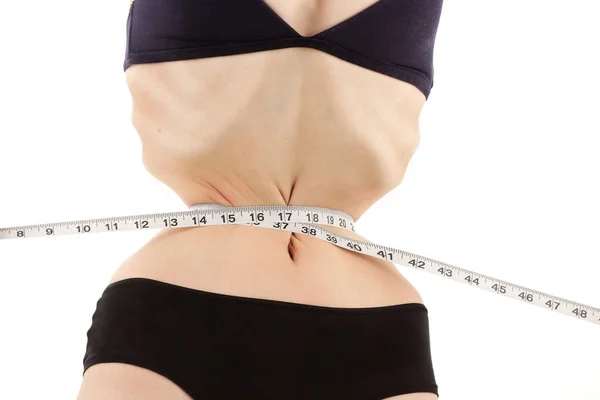 Одержимая молодая женщина с анорексией измеряет свое худое тело — стоковое фото