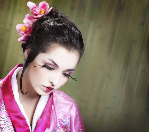 Молодая гейша в платье кимоно на фоне зеленого бамбука — стоковое фото