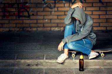 Karanlık kapı aralığında bira ile oturan umutsuzluk genç kız 