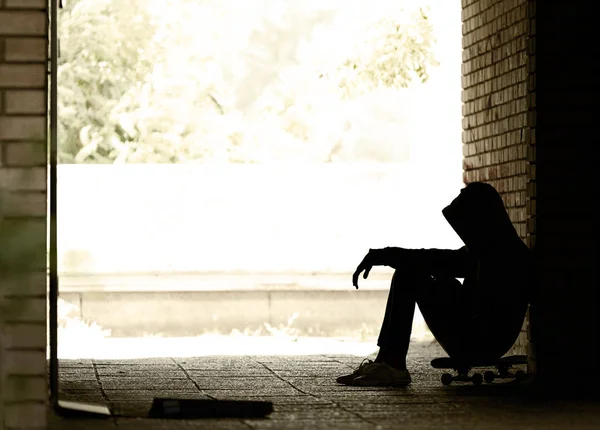 Silhouette d'un adolescent sur une planche à roulettes dans une passerelle — Photo