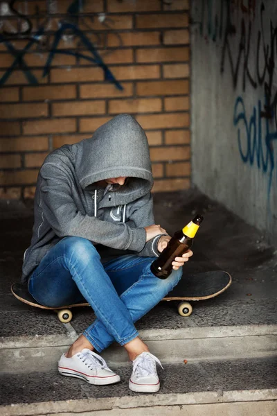 Solitaria adolescente sentada con una botella de cerveza en la entrada —  Fotos de Stock