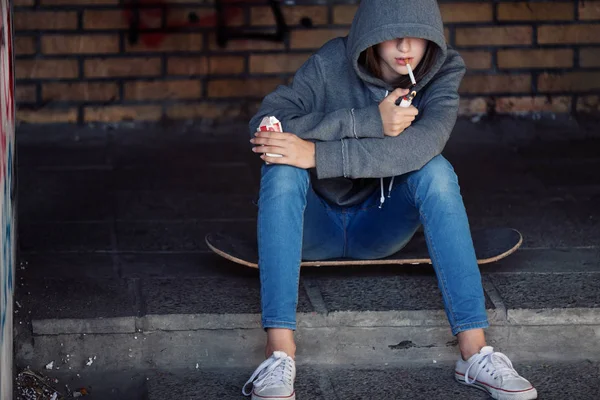 Magányos tinédzser lány ül, és a dohányzás cigaretta ajtó — Stock Fotó