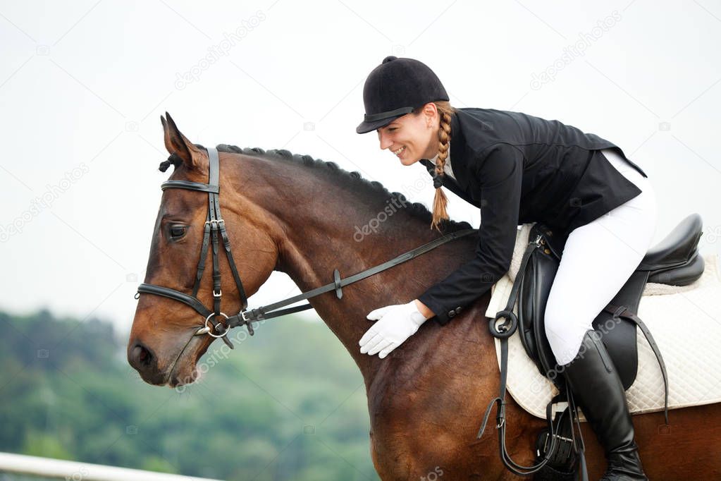 Attractive Young Woman in Jockey suit Stroking her Horse