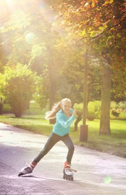 Silindirler üzerinde sürme ve güneşli bir sonbahar gün zevk küçük kız