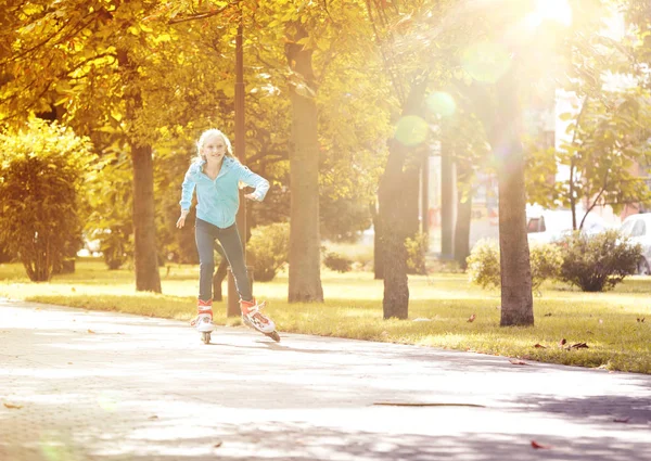 Niña montando sobre rodillos y disfrutando del soleado día de otoño —  Fotos de Stock