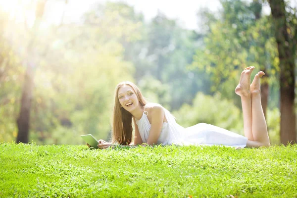 Jovem mulher deitada com Tablet no belo prado verde — Fotografia de Stock