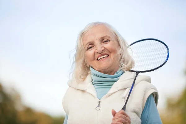 Starší žena hraje tenis venku — Stock fotografie