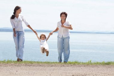 Anne ve iki kızı birlikte su manzaraya oynama