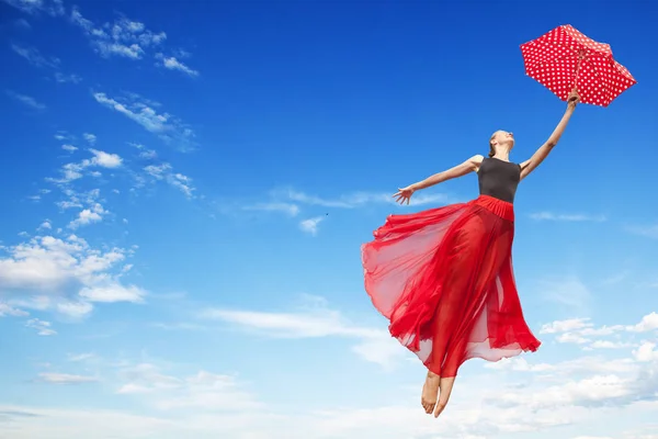 Junge Frau fliegt mit rotem Regenschirm in den Himmel — Stockfoto
