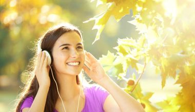 Mutlu kız harika bir sonbahar gününde kulaklık dinleme