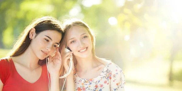 Chicas felices escuchando auriculares en un maravilloso día de otoño —  Fotos de Stock