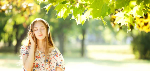 Chica feliz escuchando a los auriculares en un maravilloso día de otoño —  Fotos de Stock