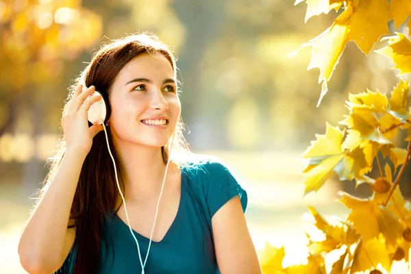 Ευτυχισμένος κορίτσι ακούτε τα ακουστικά σε μια υπέροχη μέρα του φθινοπώρου — Φωτογραφία Αρχείου