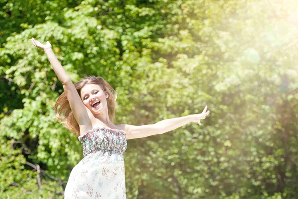 Glückliche junge Frau genießt den Sommer auf der grünen Wiese. — Stockfoto