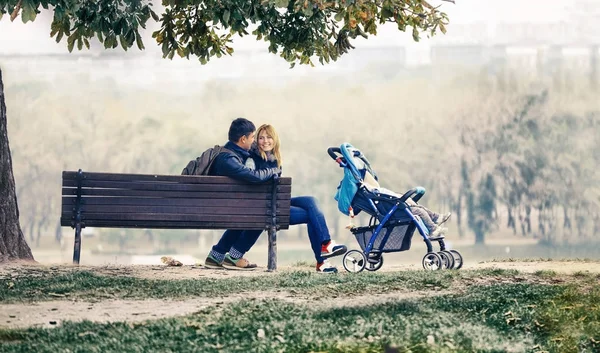 Happy νεαρό ζευγάρι κάθεται με ένα μικρό γιο το Baby μεταφορά — Φωτογραφία Αρχείου