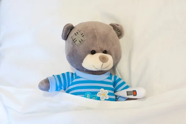 Yumuşak oyuncak ayı bir termometre holding ve sıcaklığının ölçülmesi — Stok fotoğraf