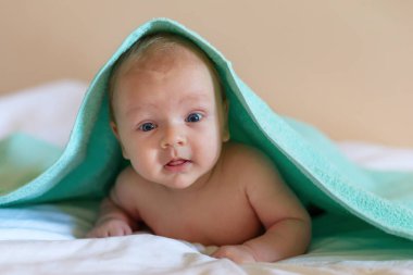 küçük çocuk bebek poz ve gülümseyen bir havlu altında