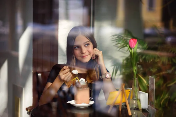 Girl drinks coffee and watches video on mobile phone — Stock Photo, Image