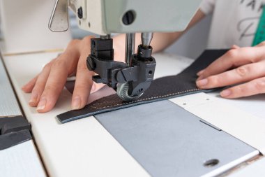 Kız dikiş makinesine dikiş dikiyor kumaş ve deri karalayıp ürün yapıyor.