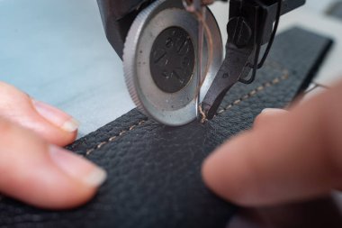 Kız dikiş makinesine dikiş dikiyor kumaş ve deri karalayıp ürün yapıyor.