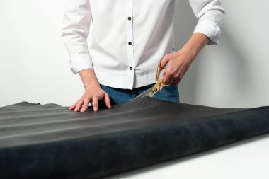 Usta makasla masanın üzerinde büyük bir parça siyah deri keser.