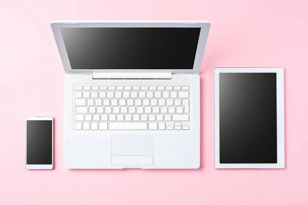 Technology background with modern white computer, tablet and smart phone on pink background