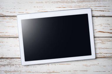 Eski bir ahşap masa üzerinde beyaz dijital tablet