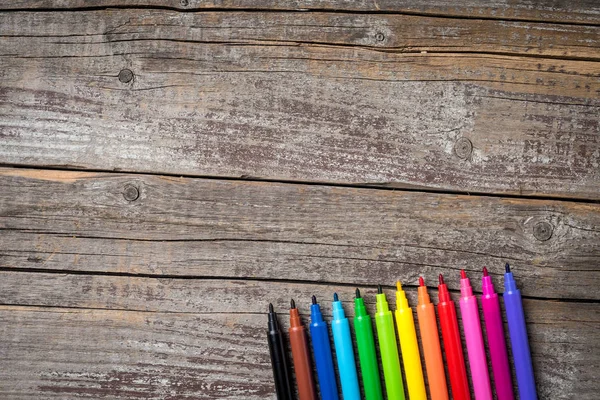 Overhead shot of colorful markers on wooden table