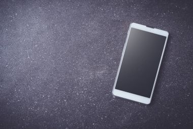 Karanlık taş masada beyaz akıllı telefon