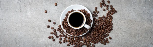 Xícara de café com grãos de café no fundo de pedra cinza — Fotografia de Stock