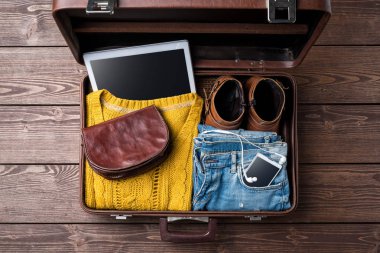 Ahşap masa üzerinde rahat kadın kış giysileri ile açık bavul.