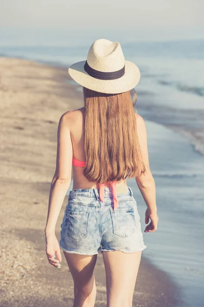 Genç bir kadın sahilde yürüyor.