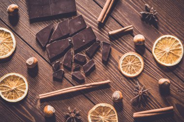 Kuru portakal dilimleri, tarçın ve ahşap masa üzerinde fındık ile koyu çikolata bar