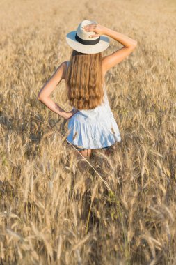 Hasır şapka ve beyaz gömlek altın buğday alanında güzel genç kadın