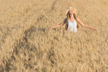 Hasır şapka ve beyaz gömlek altın buğday alanında güzel genç kadın