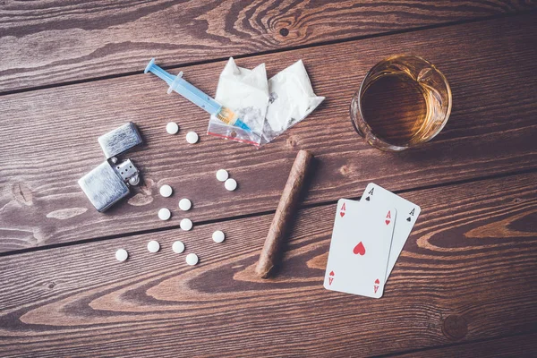 Hard drugs with pills, playing cards, syringe and alcohol on wooden table — Stock Photo, Image