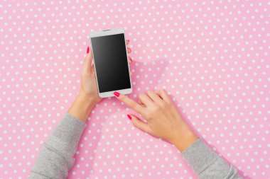 Pembe noktalı arka plan üzerinde beyaz akıllı telefon kullanarak eller