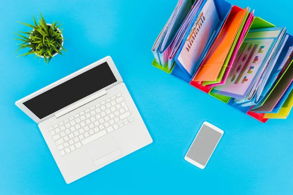 Blue office table with laptop and documents