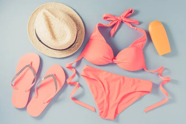 Pink swimsuit with beach accessories on blue background — Stock Photo, Image